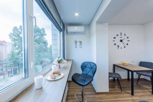 a dining room with a table and a clock on the wall at CityApartments Kyiv Heroiv Dnipra in Kyiv