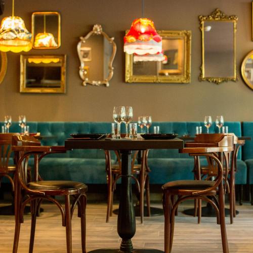 a dining room with tables and chairs and mirrors at Logis Hôtel Le Glacier in Orange