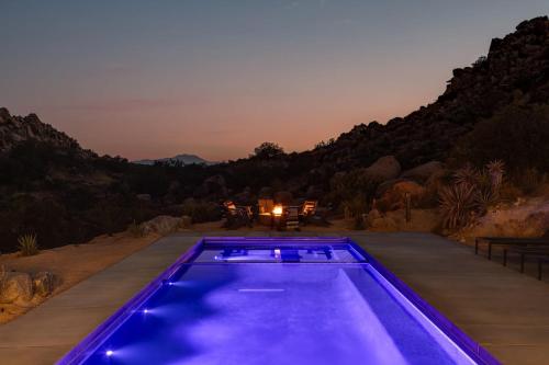 a swimming pool in the middle of a yard at night at Whistling Rock By The Cohost Company in Yucca Valley Service Center Heliport