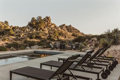a group of chairs sitting next to a swimming pool at Whistling Rock By The Cohost Company in Yucca Valley Service Center Heliport