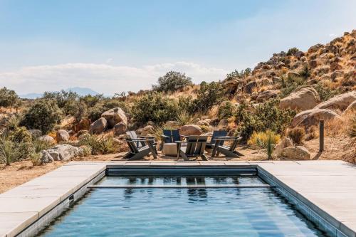 a swimming pool with two chairs and a table at Whistling Rock By The Cohost Company in Yucca Valley Service Center Heliport
