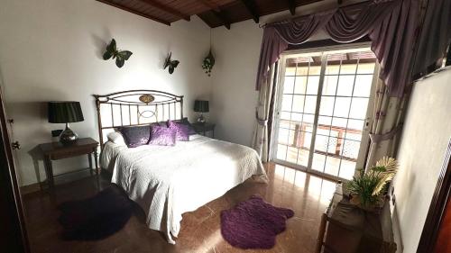 a bedroom with a bed with purple pillows and a window at Villa Lujo y Relax in Adeje by Deihu Experiences in Adeje