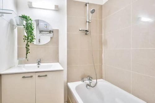 une salle de bain avec un lavabo, une baignoire et un miroir dans l'établissement GuestReady - Bright Stay in the Heart of Paris, à Paris