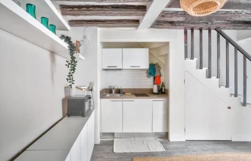 une cuisine avec des armoires blanches et un évier dans l'établissement GuestReady - Bright Stay in the Heart of Paris, à Paris