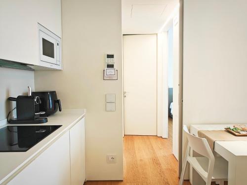 a white kitchen with a microwave and a table at StarPalace Elegance Apartment Jesolo SPA GYM POOL PARKING - a 2 passi dal mare in Lido di Jesolo