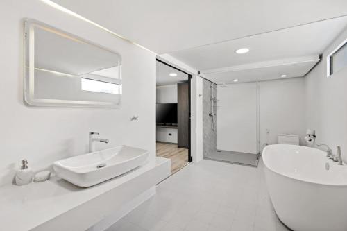 a white bathroom with a sink and a mirror at Beach Walk Condo 3br in Replay residence in Bang Rak Beach