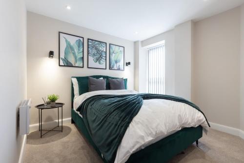 a bedroom with a bed with a green comforter at Central Leeds Apartment by the Arena with on-site parking in Leeds
