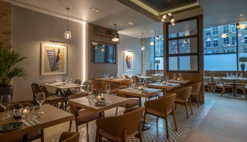 a restaurant with tables and chairs and windows at Maldron Hotel Shoreditch London in London