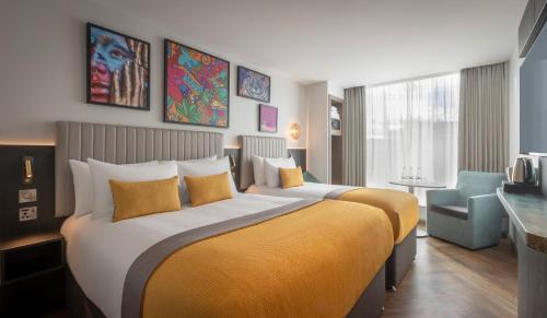 a hotel room with a large bed and a chair at Maldron Hotel Shoreditch London in London