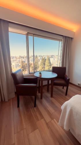 a room with a table and chairs and a large window at Bariloche Studio Center Leg.1068 in San Carlos de Bariloche