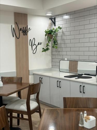 a kitchen with white cabinets and a table and a table and chairs at Prestige Prince George Lodge in Prince George