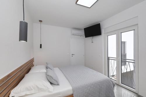 a white bedroom with a bed and a window at Vila Beny in Vir