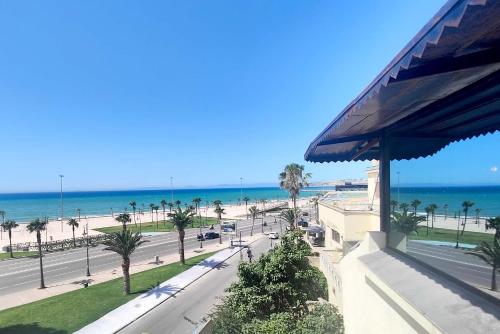 a view of a beach with palm trees and the ocean at Villa Mirasol Hotel in Tangier