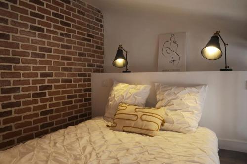 - un lit avec deux oreillers et un mur en briques dans l'établissement Studio calme aux portes de Paris, à Saint-Denis