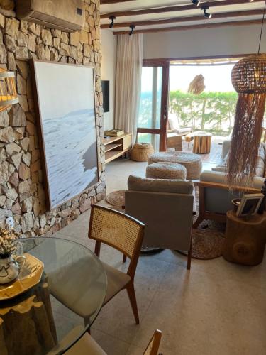a living room with a stone wall at Casa Tangerina BG, seu Bangalô frente mar em Barra Grande-PI in Barra Grande
