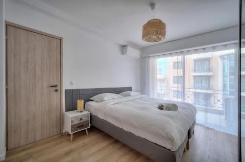 une chambre avec un grand lit et une grande fenêtre dans l'établissement 3 PIECES MODERNE PROCHE MARTINEZ et PLAGES A2B249, à Cannes