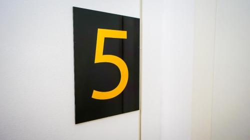 a sign with a yellow number on a wall at GLOW Apartment in Magdeburg