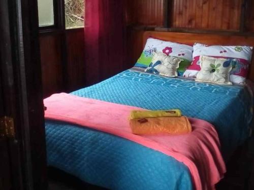 a bed with a blue comforter and pillows at Madervillhospedaje in Aquitania