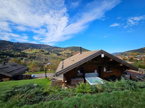 a house with a roof on a grass field at Chalet ''la cabane ô Pierres'' 12 pers spa et sauna in Ventron