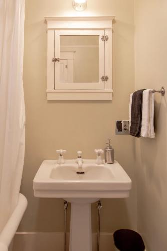 a bathroom with a white sink and a mirror at The Historic Benham-Johnston Bungalow in Sheridan