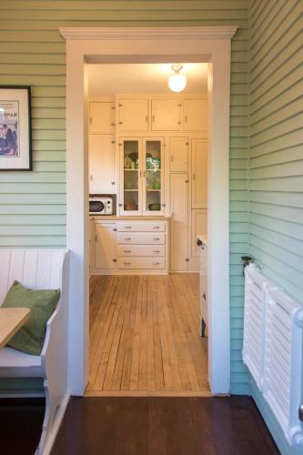 a kitchen with white cabinets and a wooden floor at The Historic Benham-Johnston Bungalow in Sheridan