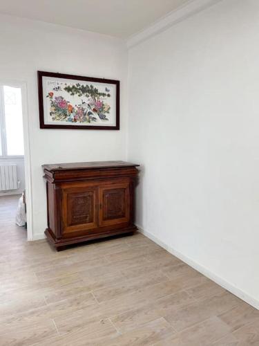 Cette chambre blanche dispose d'une armoire en bois et d'une photo murale. dans l'établissement Appartement Charpenne, à Villeurbanne