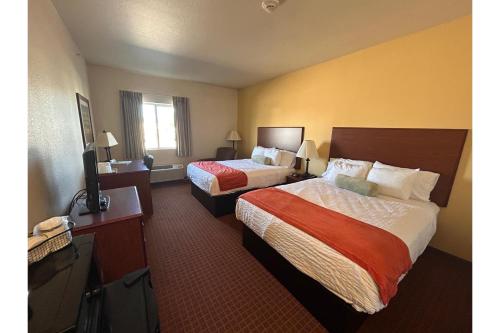 ein Hotelzimmer mit zwei Betten und einem Fernseher in der Unterkunft Park View Inn & Suites, Hoisington in Hoisington