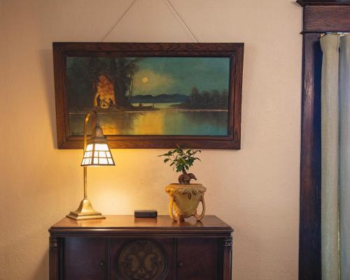 a table with a lamp and a painting on the wall at The Historic Benham-Johnston Bungalow in Sheridan