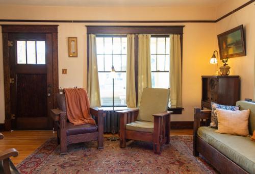 a living room with chairs and a couch and windows at The Historic Benham-Johnston Bungalow in Sheridan