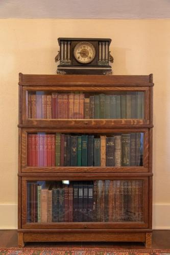 a book shelf filled with books with a clock on top at The Historic Benham-Johnston Bungalow in Sheridan