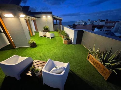 a rooftop patio with white chairs and green grass at Kastro Hotel in Heraklio Town