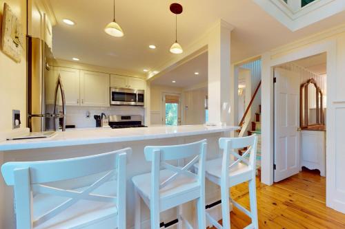 a kitchen with white cabinets and blue stools at Seaside Sanctuary in Harwich