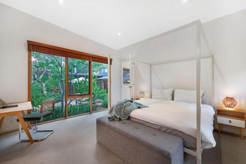 a bedroom with a large white bed and a desk at Kurraburra Lodge in Anglesea
