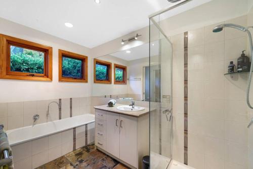 a bathroom with a tub and a sink and a shower at Kurraburra Lodge in Anglesea