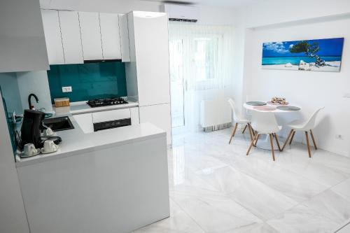 Una cocina con gabinetes blancos y una mesa y sillas. en Zain Apartament, en Craiova