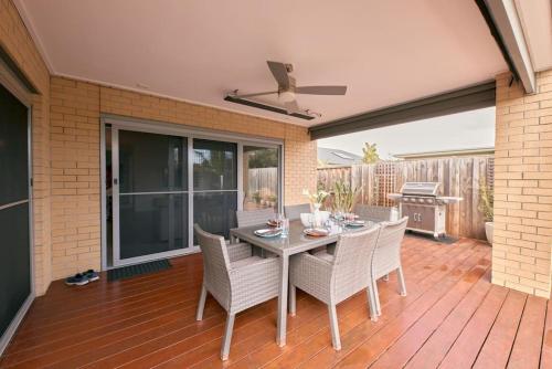 a patio with a table and chairs on a deck at Zeally Sands Pool Retreat in Torquay