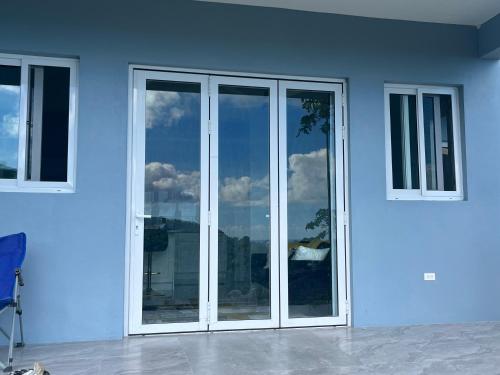 a white building with glass doors and windows at Exquisitely Threadfall in Cane Garden Bay