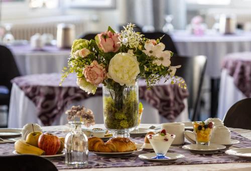 a table topped with a vase of flowers and pastries at Grand Hôtel Du Nord in Vesoul