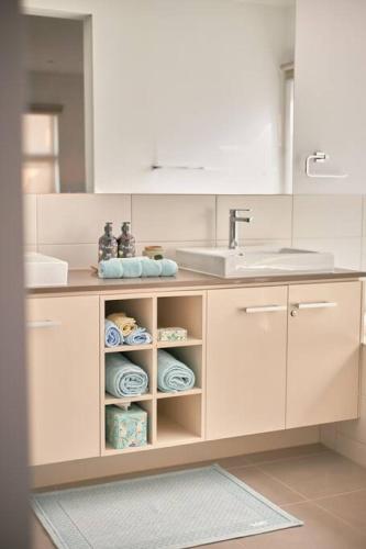 a bathroom with a sink and a counter with towels at Zeally Sands Pool Retreat in Torquay