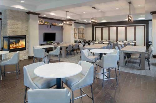 a restaurant with tables and chairs and a fireplace at Hampton Inn Lewiston-Auburn in Lewiston