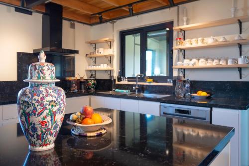 a kitchen with a vase and a bowl of fruit on a counter at Urla Köstem Müze Otel in Uzunkuyu