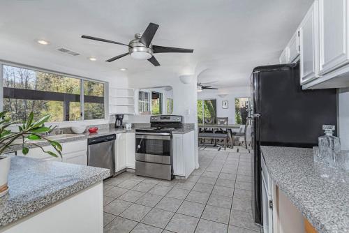 Una cocina con gabinetes blancos y un refrigerador negro. en Sequoia Riverfront House With Beach Access, en Three Rivers
