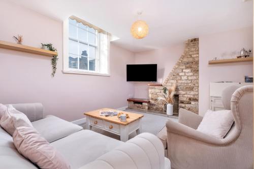 a living room with white furniture and a fireplace at Lambert Cottage - In the Heart of Stamford in Stamford