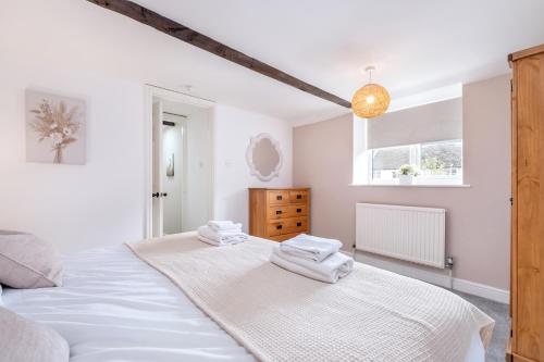 ein Schlafzimmer mit einem großen weißen Bett mit Handtüchern darauf in der Unterkunft Lambert Cottage - In the Heart of Stamford in Stamford