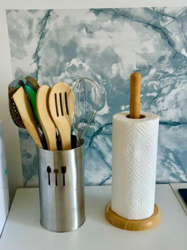 un contenant d'ustensiles de cuisine sur un comptoir à côté d'une serviette en papier, dans l'établissement Beau appartement à Ault, à Ault