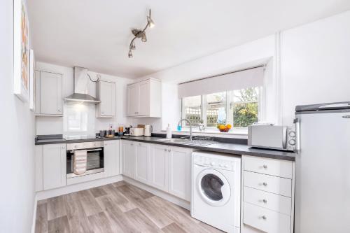 a white kitchen with a washer and dryer at Lambert Cottage - In the Heart of Stamford in Stamford