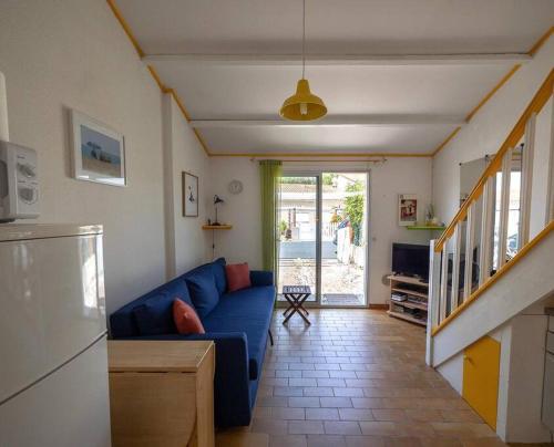 un salon avec un canapé bleu et une cuisine dans l'établissement Charmante maison proche plage, à Saint-Cyprien