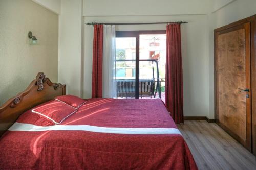 a bedroom with a bed with a red blanket and a window at Urla Köstem Müze Otel in Uzunkuyu