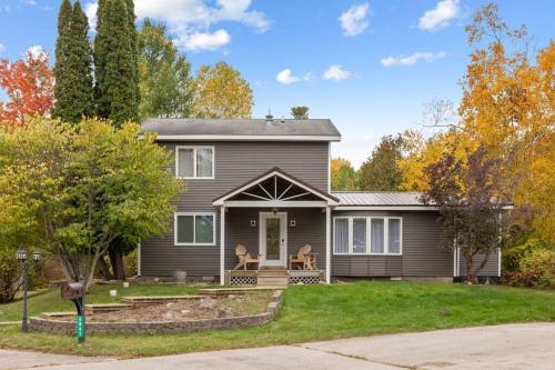a gray house with two chairs on the front porch at Long Lake Escape, Modern 3 Bedroom, Lower Unit of Duplex Home, Minutes to Downtown Traverse in Traverse City