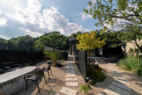 un jardín con sillas, mesas y una valla en Yeojuhyeon Dongcheon, en Chilgok